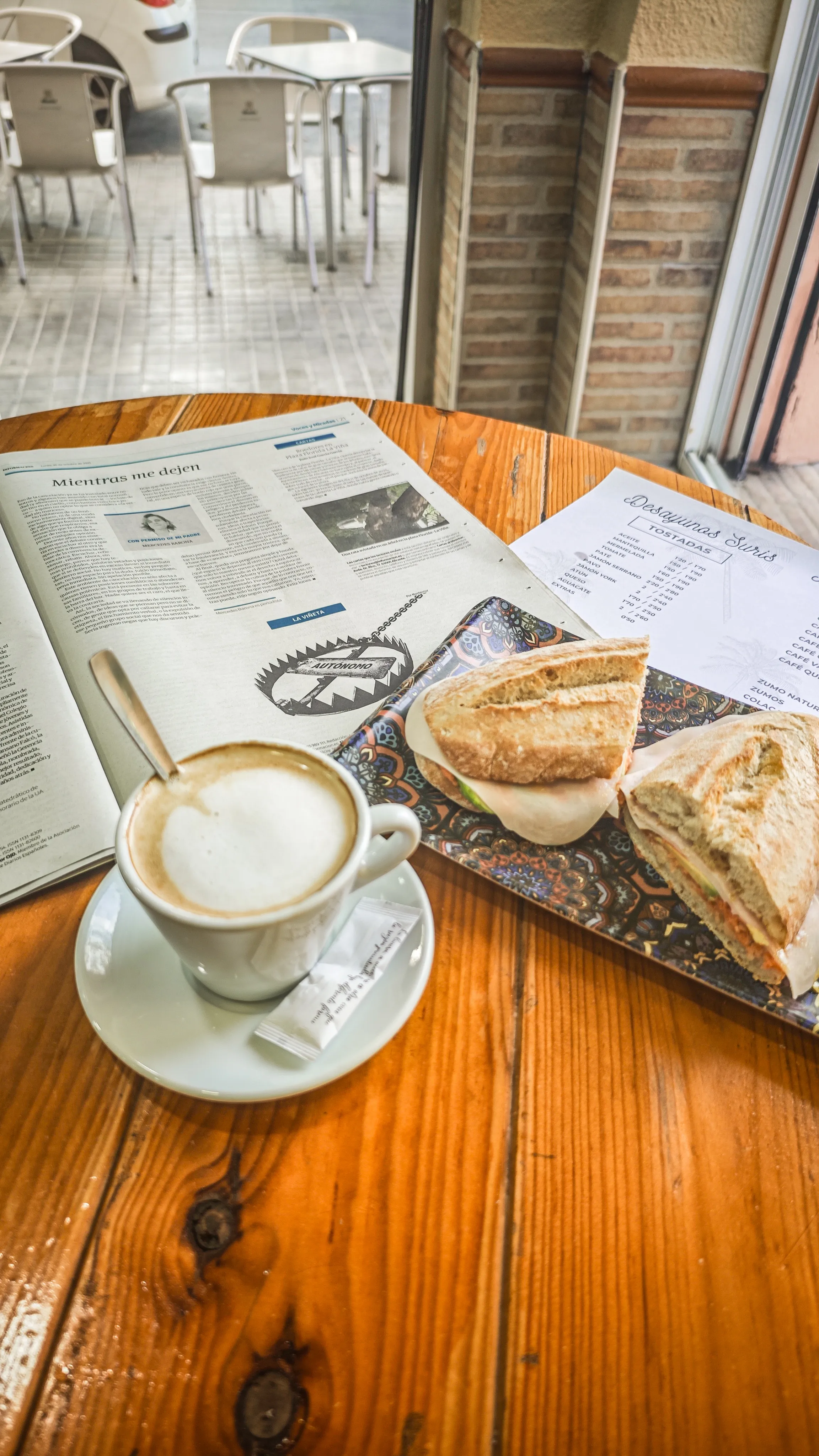 Café con leche, bocadillo y el periódico del día junto a la ventana