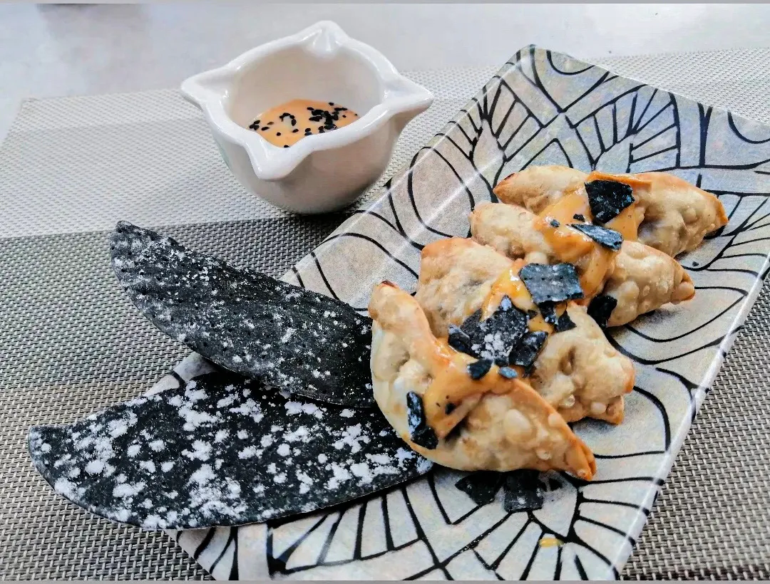 Gyozas con salsa y alga nori sobre un plato decorado
